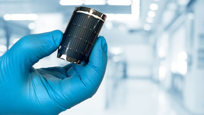 A hand in the lab holding a flexible CIGS solar cell (image: EMPA)